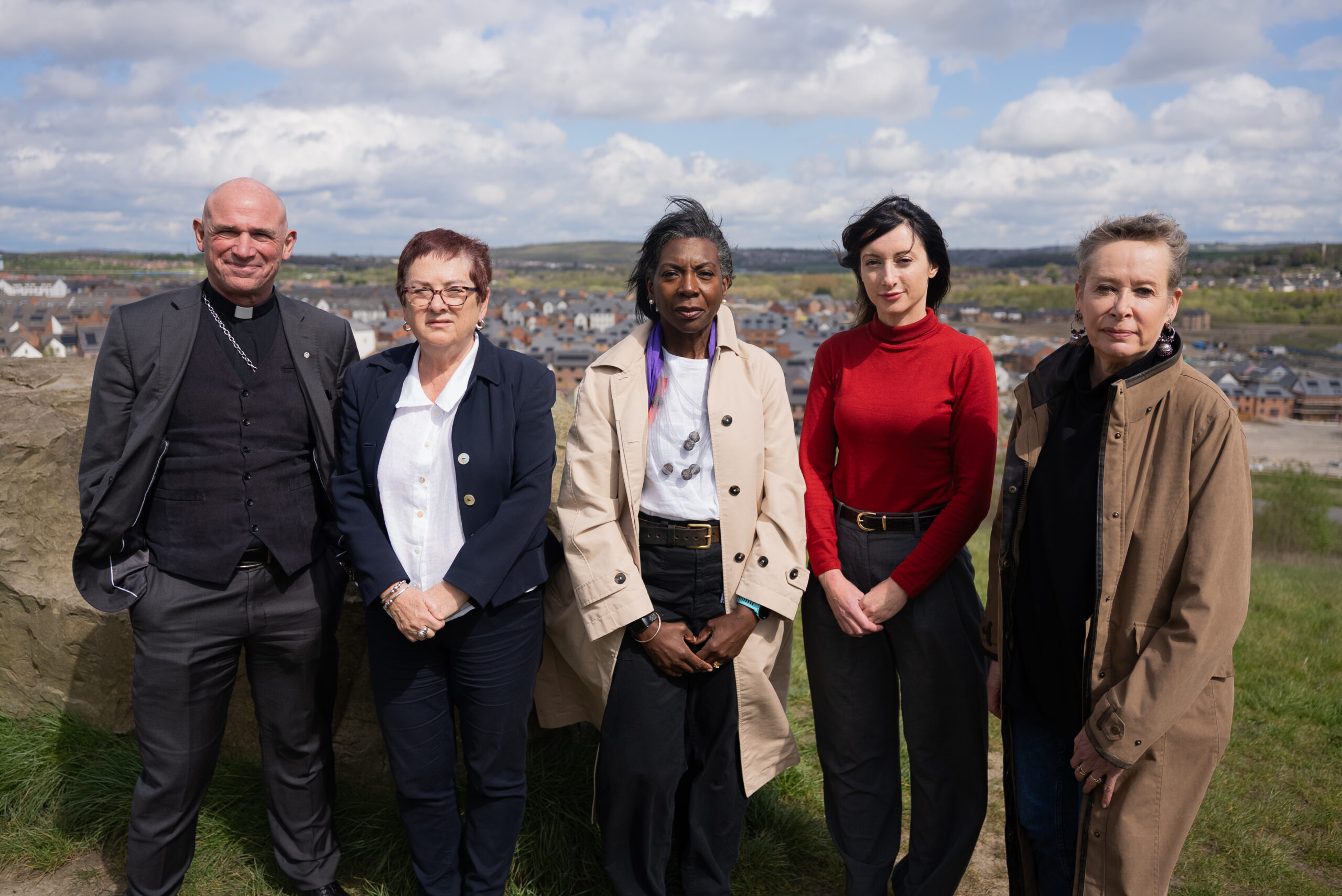 Five members of the Orgreave Chair and Panel stand outdoors on a hillside overlooking the Orgreave area. Pictured left to right are Bishop Pete Wilcox, Baroness Mary Bousted, Wendy Williams CBE, Dr Joanna Gilmore and Dr Angie Sutton-Vane.